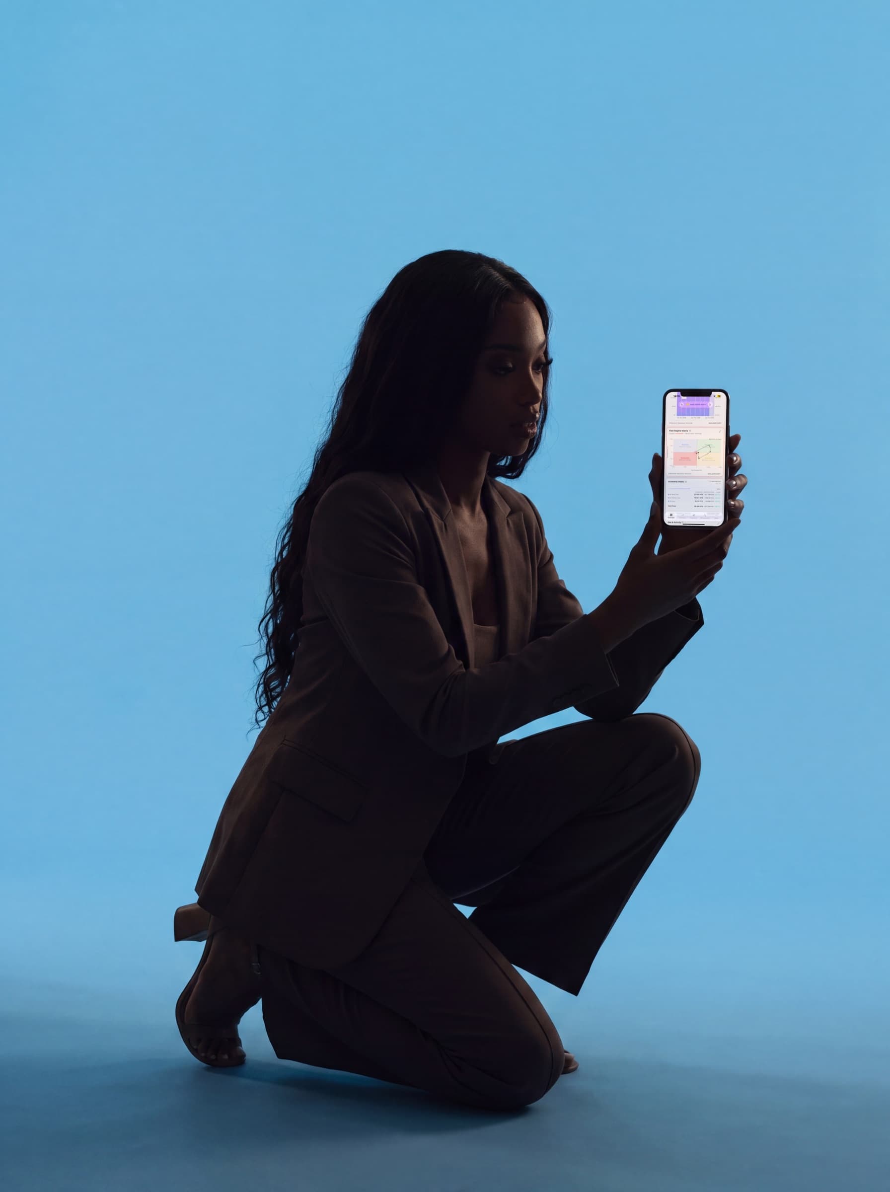 Terminal on mobile — extended-arm studio portrait of an investor showing the live regime feed